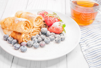 Healthy breakfast. Black tea and pancakes rolls with fresh berries and chocolate
