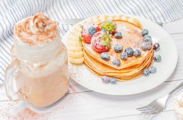 Healthy breakfast, coffee or cappuccino and homemade pancakes with fresh berries and banana
