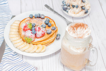 Healthy breakfast, coffee or cappuccino and homemade pancakes with fresh berries and banana