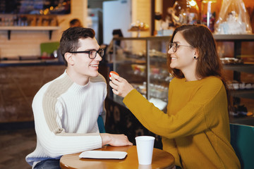 Two cute young men and a girl in a cafe.
