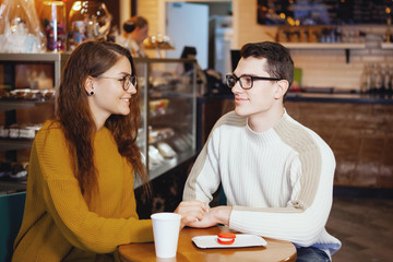 Two cute young men and a girl in a cafe.
