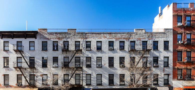 Exterior view of the facade of an old brick apartment buildings with windows and fire escapes in New York City