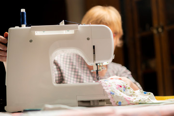 woman in glasses using sewing machine or threading on dark background b