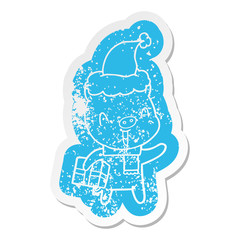 happy cartoon distressed sticker of a pig with xmas present wearing santa hat