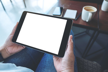 Mockup image of a woman sitting and holding black tablet pc with blank white desktop screen horizontally