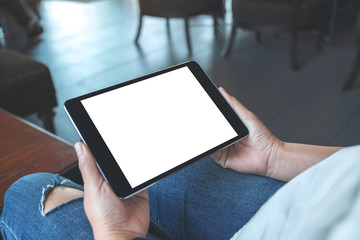 Mockup image of a woman sitting and holding black tablet pc with blank white desktop screen horizontally