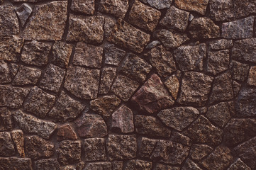 Old darkened from time to time wall with rough granite stones