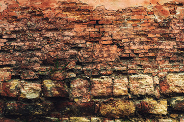 brick wall of old, red, rough brick with shabby plaster on the foundation of granite stone