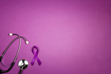 Fototapeta premium Purple epilepsy awareness ribbon with stethoscope and copy space on a purple background.
