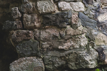 background from the Old darkened wall with granite gray roughly processed rectangular stones close-up