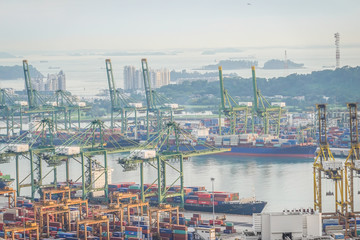 Fototapeta na wymiar Singapore - November 26, 2018:View of a container terminal at the Port of Singapore. Cargo ships docked in harbor. Ship-to-shore (STS) gantry cranes loading and unloading vessels at shipping yard.