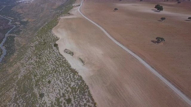 Aerial view of a badlands desert area with a dirt road.