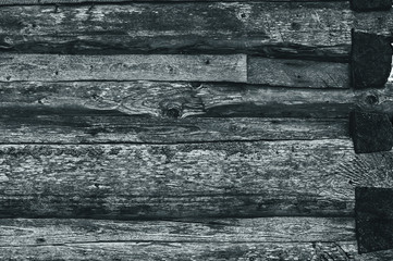 A wall made of old, dark, worn gray ashlar logs.