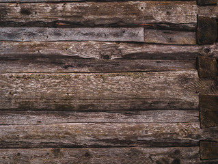 A wall made of old, dark, worn brown ashlar logs.