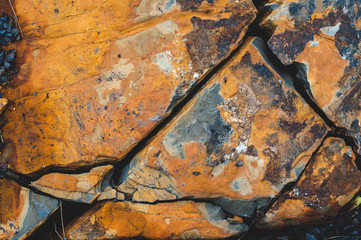 Yellow-red-brown black background from iridescent sandstone close-up