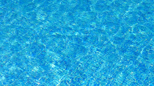 Soothing crystal clear swimming pool blue tile waters moving bright in the sun 
(medium shot)