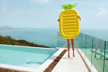 Summer vacation. Woman with pineapple float having fun near pool