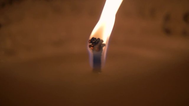 Close up of burning candle wick in low light in slow motion.