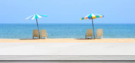 Empty white marble table over blur blue sky and sea beach with colorful umbrella in summer background, product display montage background, banner