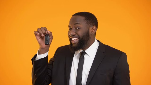 Smiling african-american male showing automobile keys, renting car, leasing