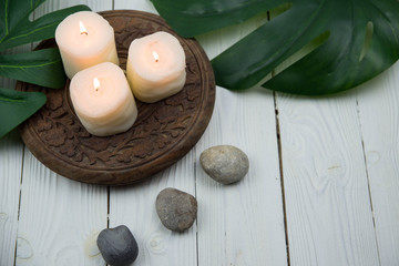 White candles, green leaves and grey stones. Concept of harmony, balance and meditation, spa, massage, relax.