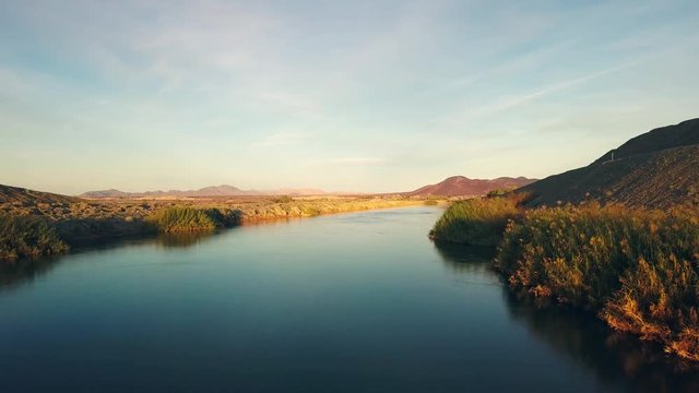 Aerial dolly, over the all American Canal during sunset, flying low showing the vegetation.