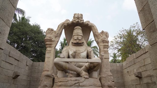 Tilt up to sky view of hypnotising stone carved statute of the Hindu god Vishnu in his Narsimha avatar, Half lion and half man in Hampi, India, Karnakata.