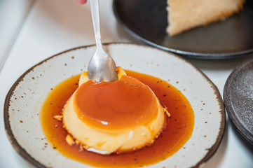 Cutting caramel pudding cake on ceramic dish