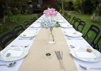 Dining set on the white table sheet with beautiful bouquet flower outdoor