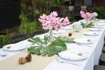 Dining set on the white table sheet with beautiful bouquet flower outdoor
