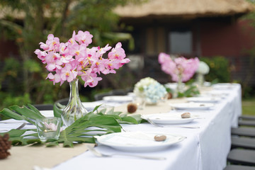 Dining set on the white table sheet with beautiful bouquet flower outdoor