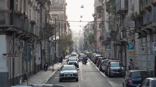 Perspective of long road up hill with medieval buildings in Catania, Italy