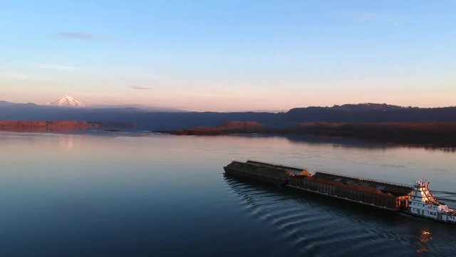 Horizontal drone shot of tugboat driving over the Columbia river with beautiful scenery.