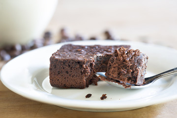 Brownie cake in white dish and black coffee on wooden table