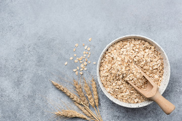 Rolled oats, oat flakes in bowl on concrete background. Top view with copy space. Healthy food,...
