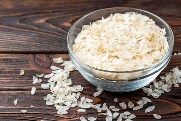Rice flakes on dark wooden background.