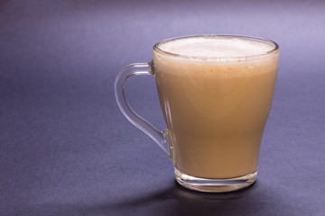 Transparent glass cup with coffee on blue background. Bright tone, soft focus