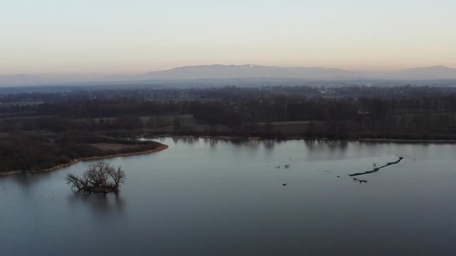 Aerial footage of a lake with mountains at  hazy sunset