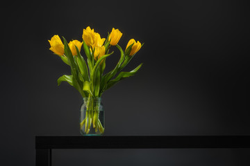 Bouquet of beautiful fresh yellow tulips in dew on dark background. Still life photo