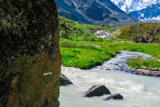 Love inscription on the stone. Akkem river and mountains view. Summer in Altai mountains