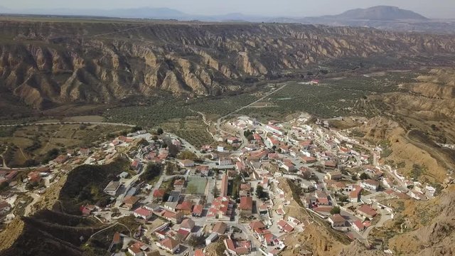 Aerial view of a town in Spain in the desert with a big cliff on the horizon.