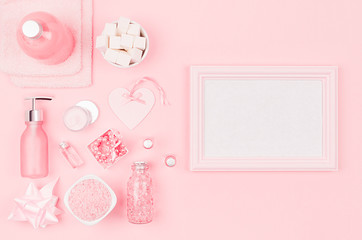 Different cosmetic products and accessories in pink and silver color with blank frame for text and advertising on soft light pink background, top view.