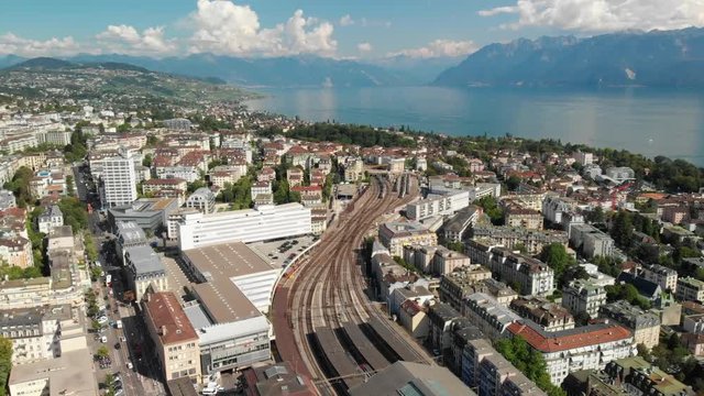 Aerial panorama drone shot circling above Lausanne CFF train station showing the city and lake Geneva in the background