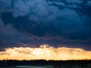 Aprilwetter, dunkle Wolken mit Sonnenlicht am Horizont