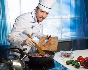 Cook in white uniform puts sliced onions in the pan