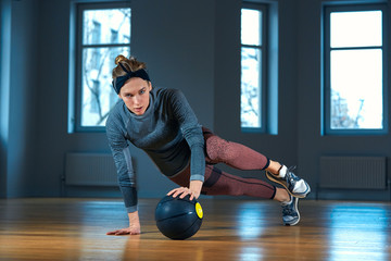 Fit and muscular woman doing intense core workout with kettlebell in gym. Female exercising at crossfit gym.
