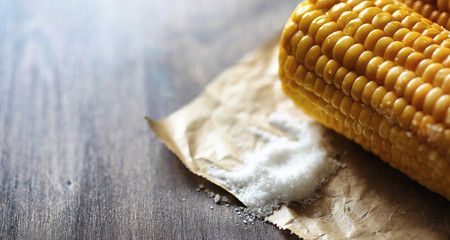 Fresh corn. Natural food from corn cob with salt. Rural Mexican food. Healthy food. Boiled and fried corn cobs on a wooden table are served with salt.