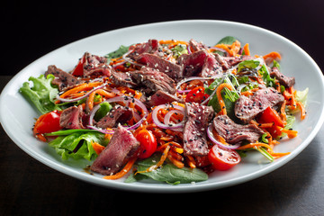 Beef salad sprinkled with sesame and garnished with onion rings.