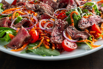 Beef salad sprinkled with sesame and garnished with onion rings.