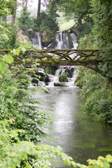 Wasserfall mit einer Holzbrücke im Vordergrund bei dem französischen Ort Le Vast